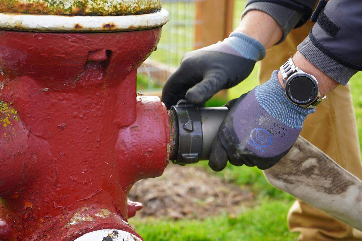 City utility worker Tyler Rouse attaches a hose to a fire hydrant for water main flushing on Tuesday, April 4, in the Columbia neighborhood of Bellingham. The work can cause temporary water discoloration that is not harmful, according to the city.