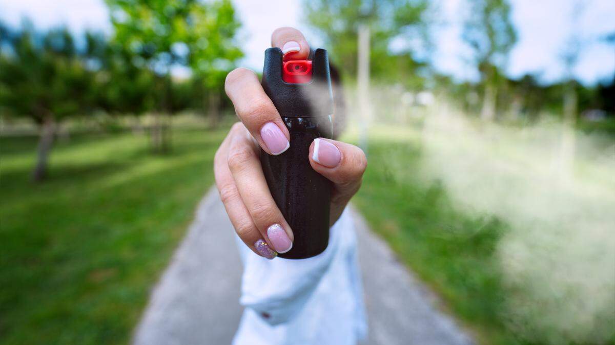 Woman using pepper spray or tear gas for self defence outdoors. High quality photo