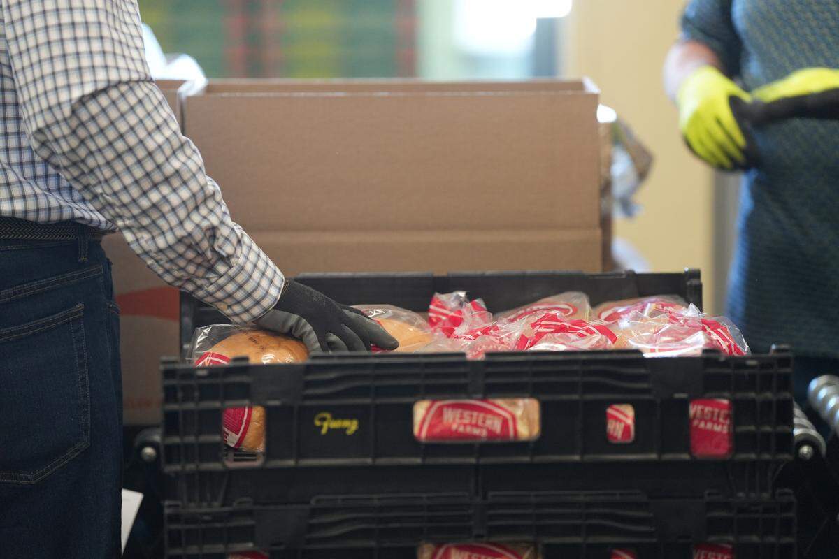 Volunteers package loaves of bread into home delivery boxes along with other staple food items at the Bellingham Food Bank.