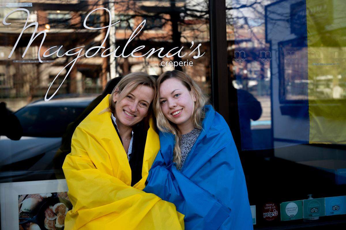 Wrapped in the colors of the Ukrainian flag, Magdalena Theisen, left, and Margo Topchaniuk pose at Magdalena’s Bistro & Creperie on Thursday, March 4, in Fairhaven. Theisen, who is from Poland, and Topchaniuk, who is from Ukraine, have been organizing donations to be sent to Ukraine to help people impacted by Russia’s invasion of the country.