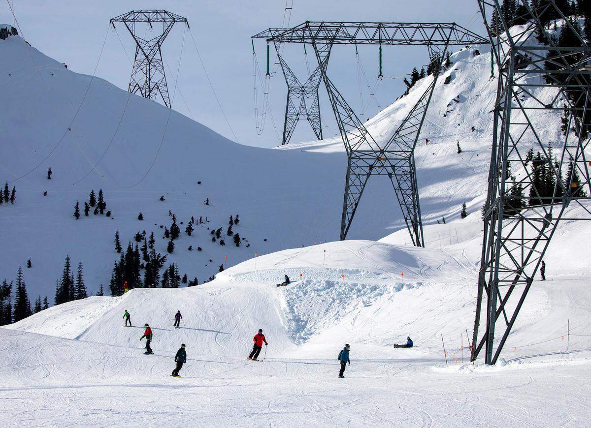 Skiers and snowboarders come down Gemini under the power lines on the back side of the mountain Friday, Jan. 28, 2022, at Stevens Pass, Washington.