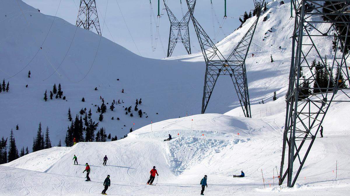 Skiers and snowboarders come down Gemini under the power lines on the back side of the mountain Friday, Jan. 28, 2022, at Stevens Pass, Washington.