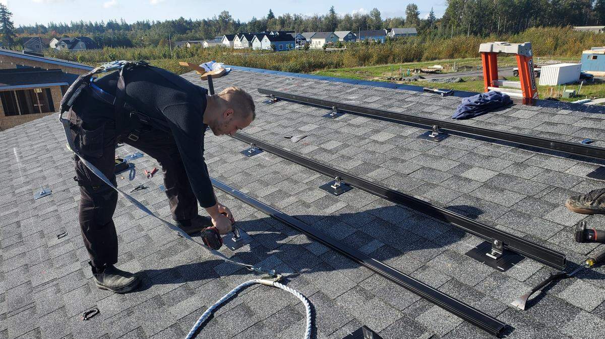 Corey Gittens of Velocity Electric installs frame mounts for solar panels on a new house in the Cordata area of Bellingham. Caitec, the developer in the area, has made solar panels a standard part of the new homes it is building in that area.