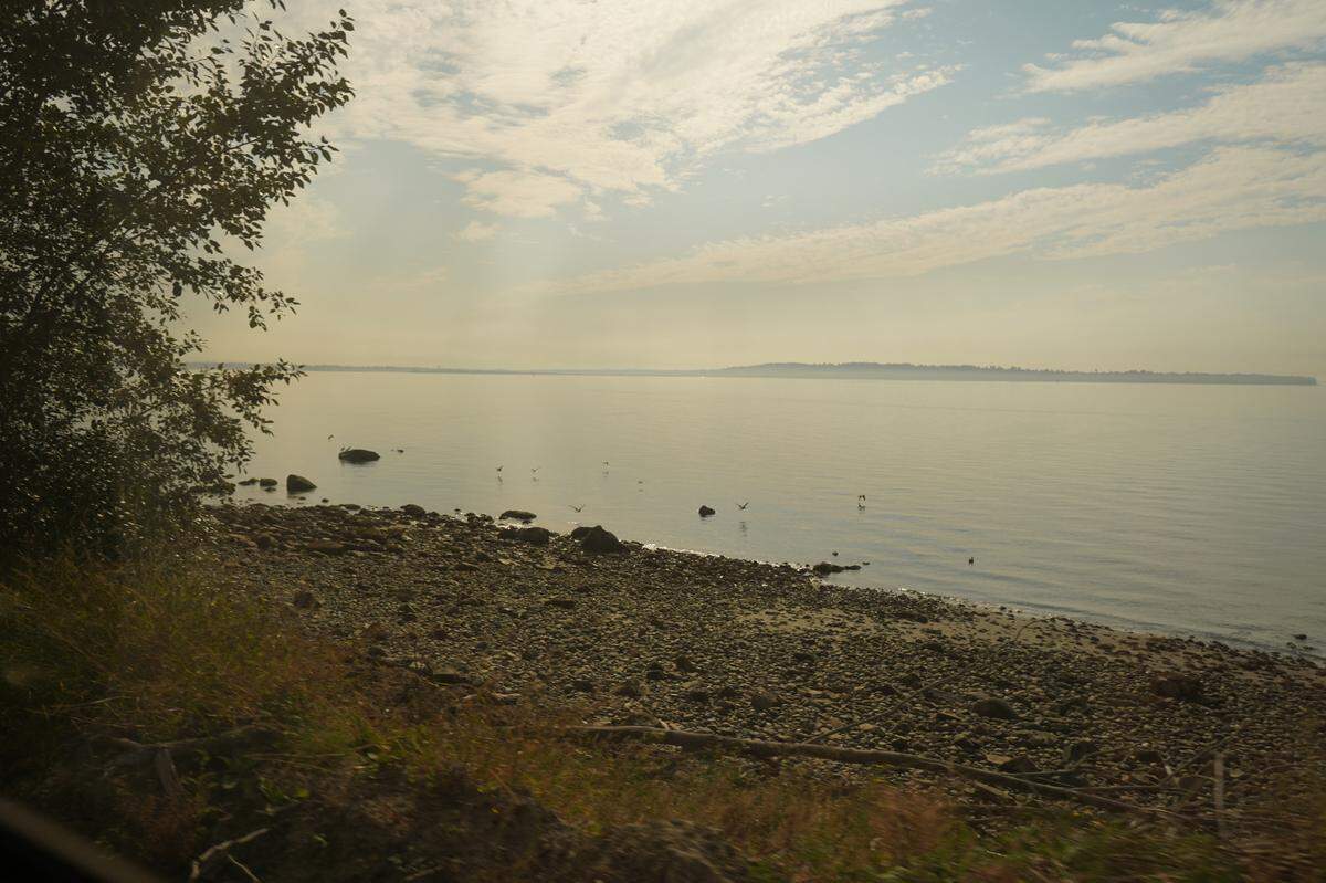 A rocky stretch of beach is visible through the window of the train along the Amtrak Cascades route on Monday, Sept. 26, in White Rock, B.C.