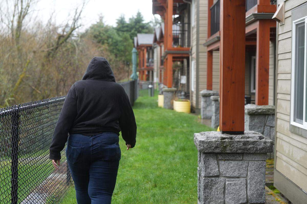 The property manager of a 104-unit apartment complex walks the fence line behind the units on March 18, 2026, in Bellingham, Wash. She said her company has had to foot a large bill for fencing and security to manage impacts from a nearby encampment