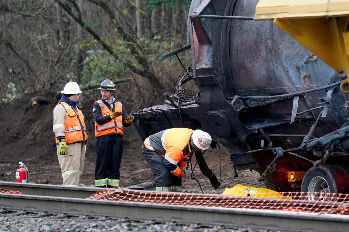 Workers begin to move one of several train cars that had been hauling crude oil and derailed a week earlier, Dec. 29, 2020, in Custer. State Sen. Doug Ericksen is urging the Legislature to examine recent allegations that a criminal act caused the oil train to derail and burn in rural Whatcom County.