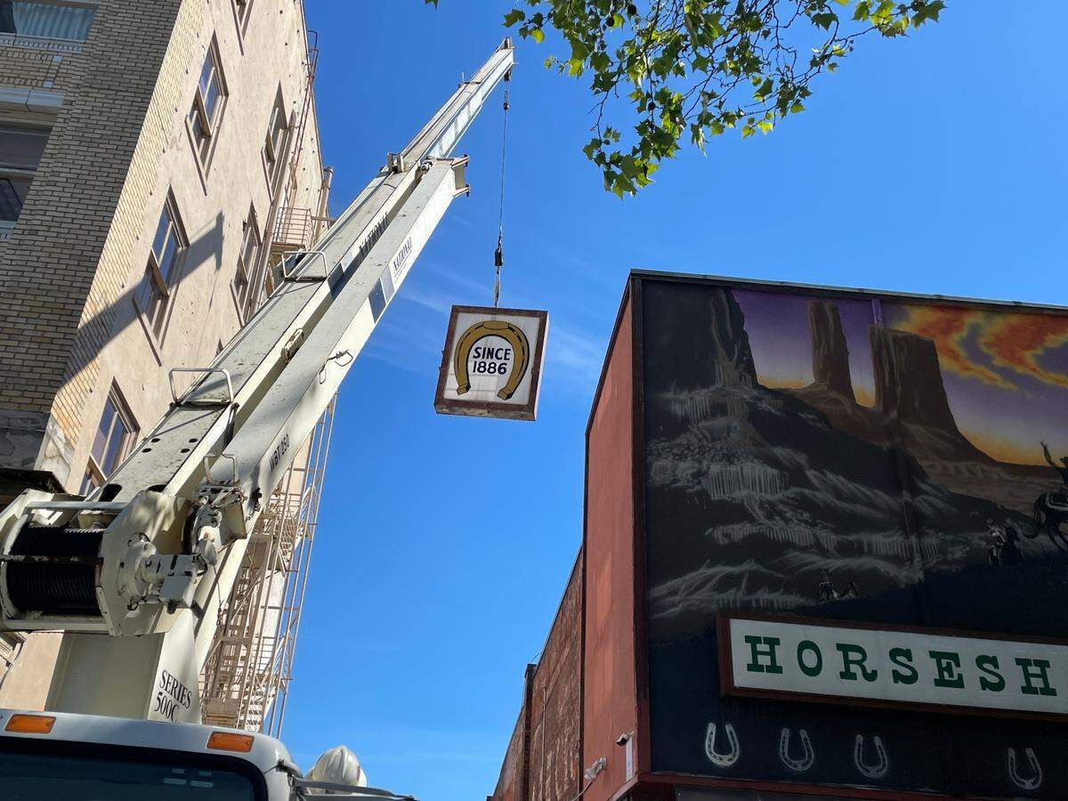 Part of the Horseshoe Cafe sign is lowered onto a truck on Tuesday, June 7. The longtime Bellingham cafe is getting a new sign that will have a similar look but will be safer and have new features.