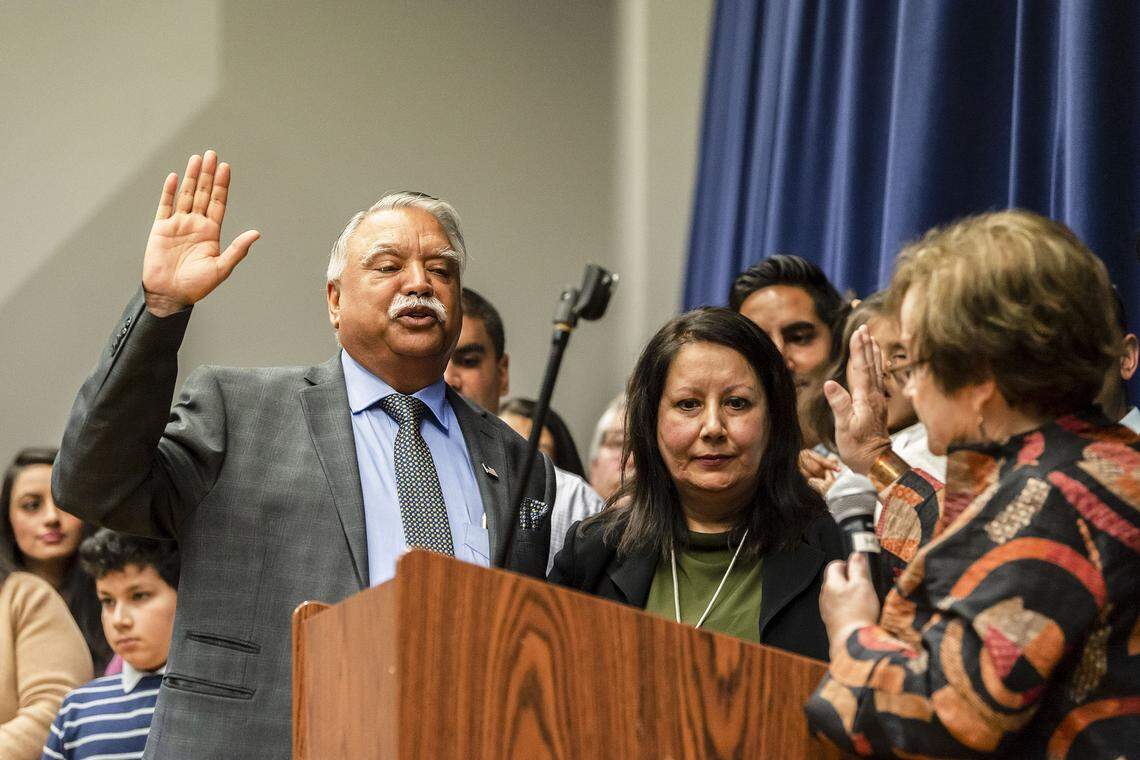 Whatcom County Executive-elect Satpal Sidhu, right, takes the oath of office from out-going Whatcom County Auditor Debbie Adelstein, right, as his wife Mundir Sidhu observes during his swearing-in ceremony on Saturday at Meridian High School in Laurel.