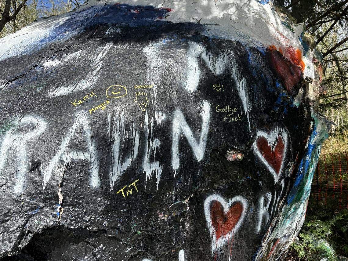 A few people signed Bellingham’s Graffiti Rock with a yellow marker on Friday, April 17, 2026, as the Washington State Department of Transportation was preparing to move the boulder to make way for a culvert replacement project.