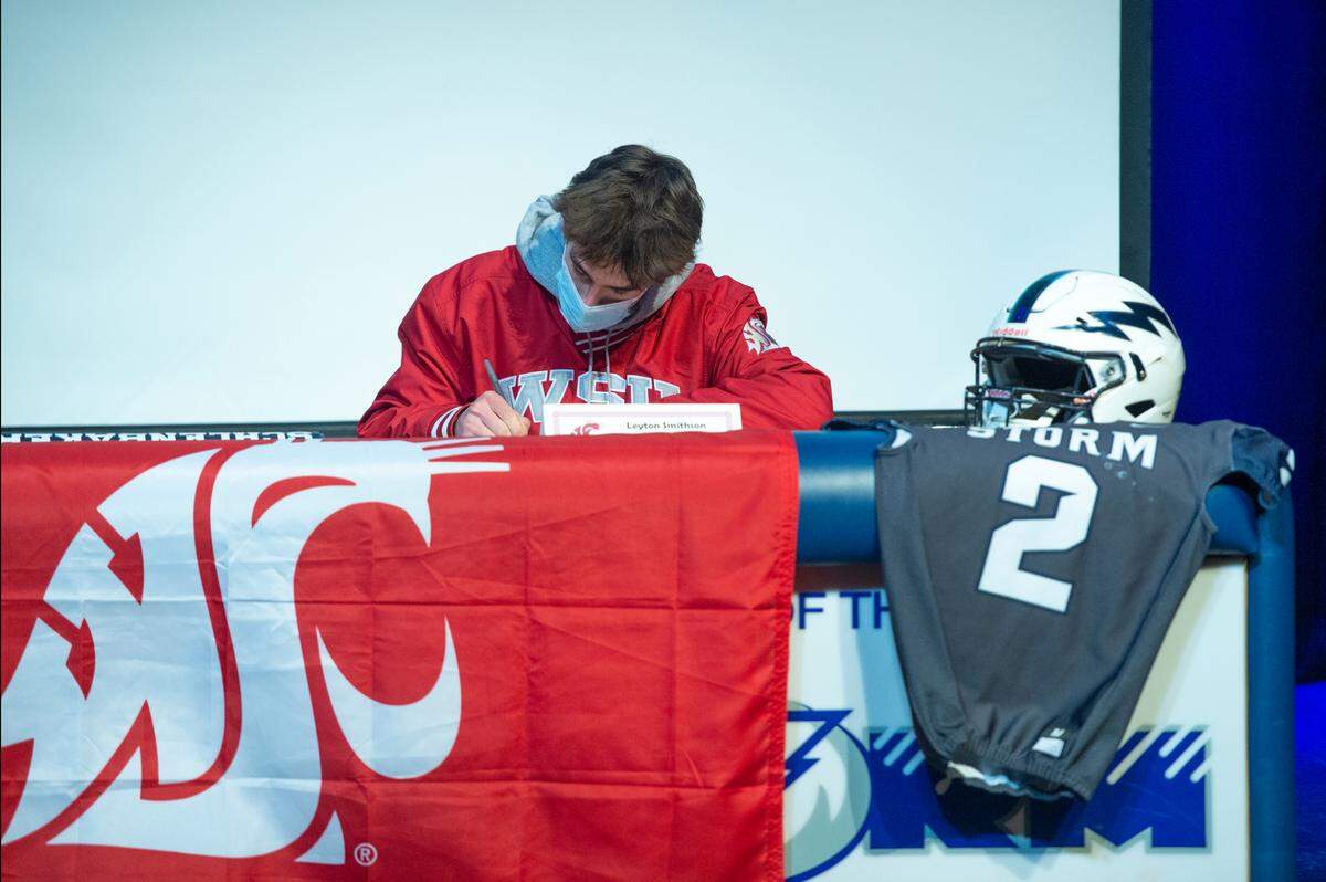 Leyton Smithson, who plays quarterback for Squalicum High School, signs his letter committing to Washington State University to play football on Wednesday, Dec. 15, 2021, in Bellingham, Wash.