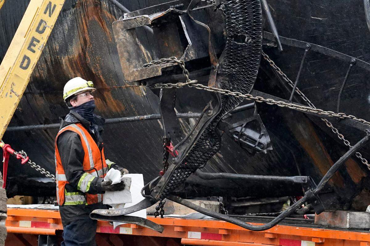 A worker looks up at a broken oil car while cleaning up residual oil Tuesday, Dec. 29, in Custer, as the train car is readied to be removed following derailment a week earlier on Dec. 22.