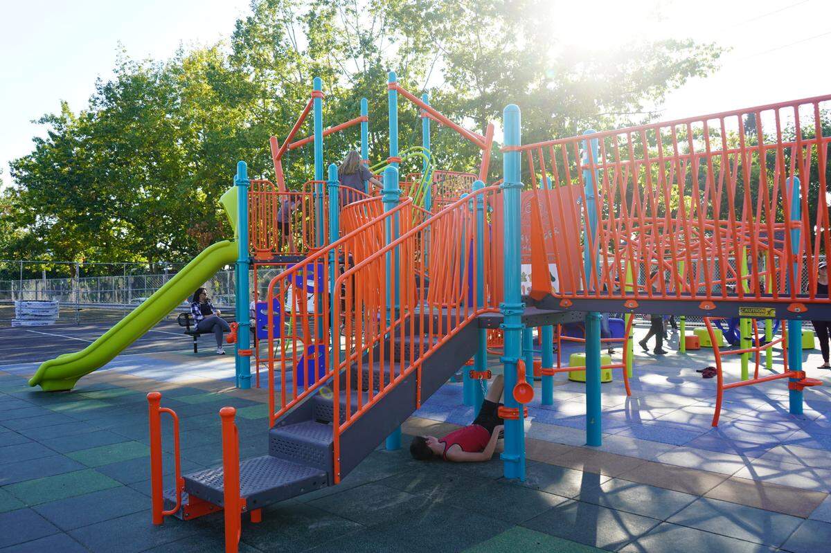Children and parents climb on the inclusive playground at Sunnyland Elementary School at an open house event in 2022 in Bellingham. Silver Beach Elementary School will get a similar inclusive playground this summer.