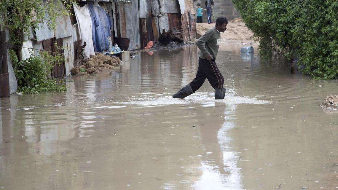 A Palestinian man walks across a flooded street on his way home following a rainstorm in Gaza City, Nov. 17, 2015.