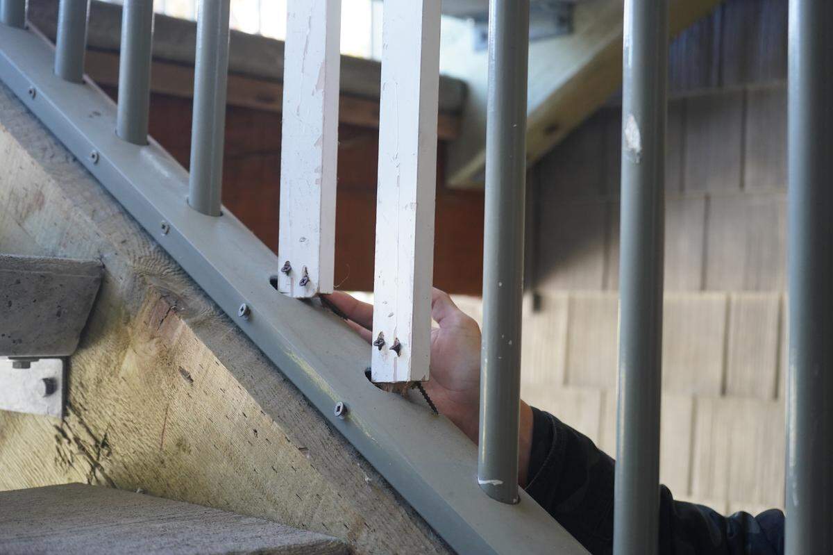 Michi Marcher, a resident at Meadow Wood Townhomes, points to two wooden posts with screws used to replace metal railing poles at the housing complex on Sept. 22, 2023, in Bellingham, Wash.
