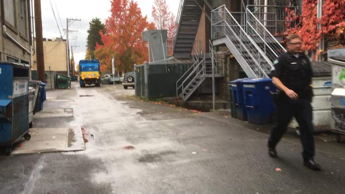 A Bellingham Police officer walks down a downtown alley Thursday afternoon as police search for a bank robbery suspect.