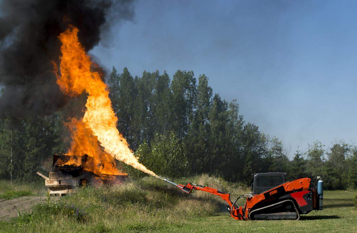 Robert Leib, owner of Eterra and Skid Steer Solutions, demonstrates his company's flamethrower near Bellingham. The flamethrower was created to show off the capabilities of the boom arm it's attached to.