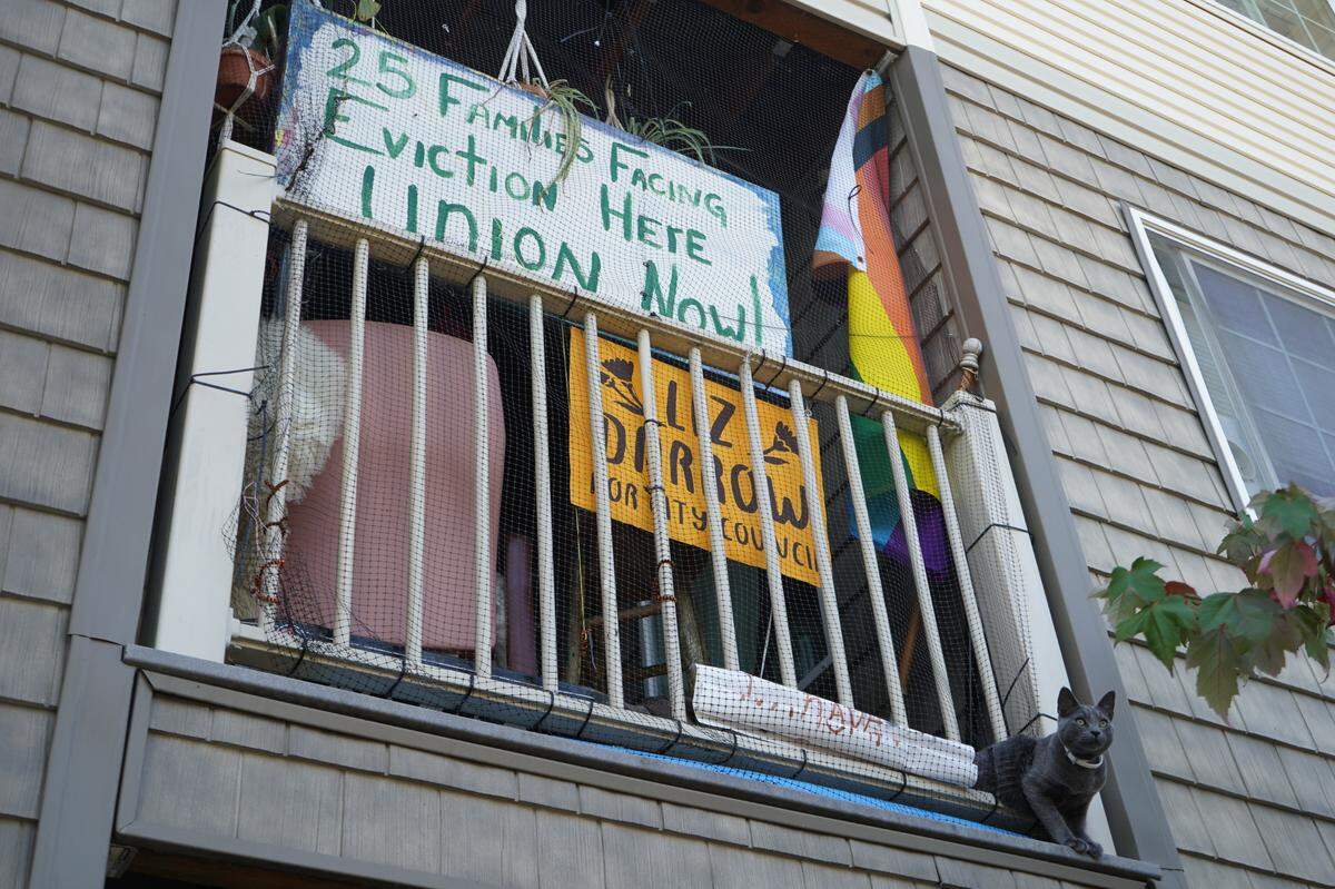 A painted sign that says ’25 families facing eviction here. Union now!’ hangs on the balcony of a residence at the Meadow Wood Townhomes on Sept. 22, in Bellingham, Washington.