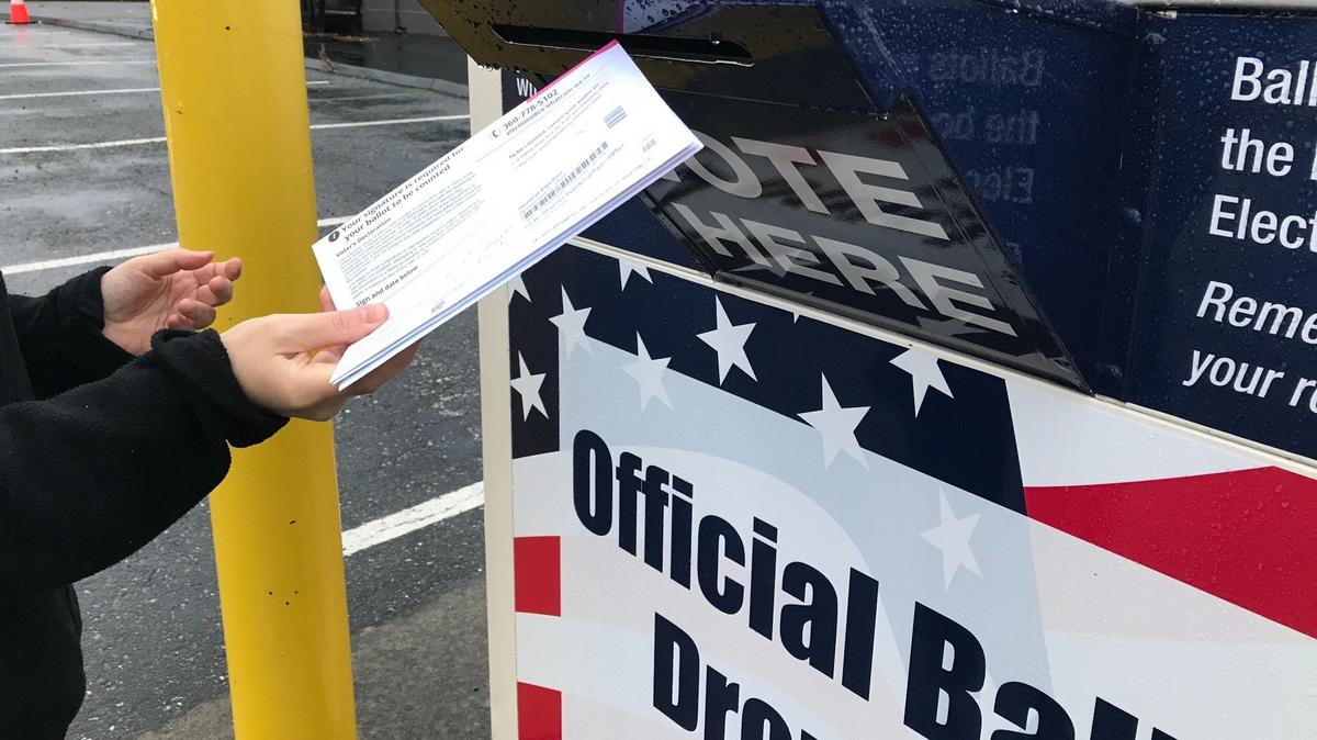 A voter uses a drop box for ballots near the Whatcom County Courthouse in Bellingham, Wash.