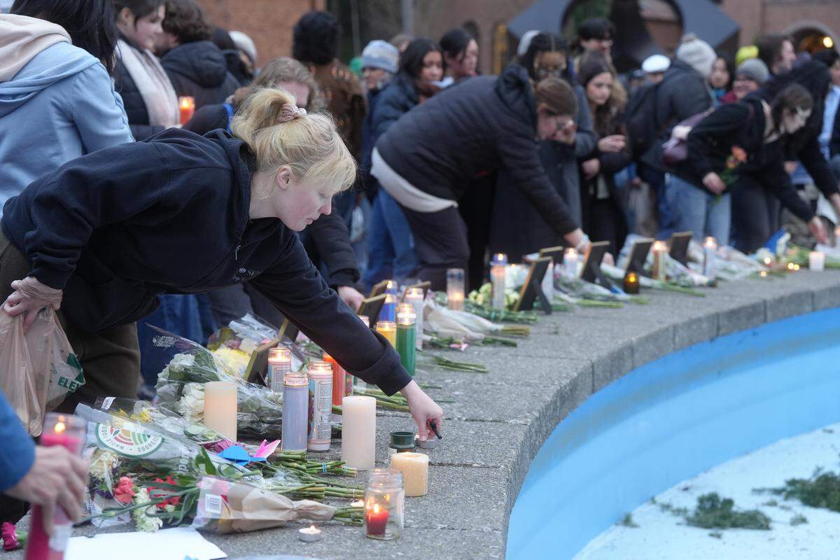 Western Washington University students and community members place flowers and candles around framed images of individuals impacted by the actions of U.S. Immigration and Customs Enforcement (ICE) agents during a vigil Monday in Bellingham.
