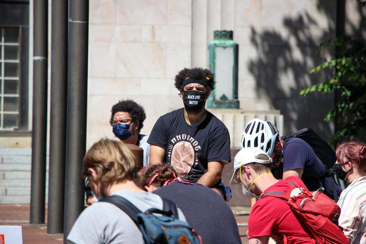 Protester at City Hall take an 8 minute and 46 second moment of silence in honor of the two-month anniversary of the death of George Floyd, the Black man killed May 25 after a white Minneapolis police officer knelt on his neck for nearly nine minutes. Around 200 people marched Saturday, July 25, in Bellingham in a protest against the presence of federal law enforcement officers in Portland, Oregon, in solidarity with the Black Lives Matter movement and in support of defunding police.