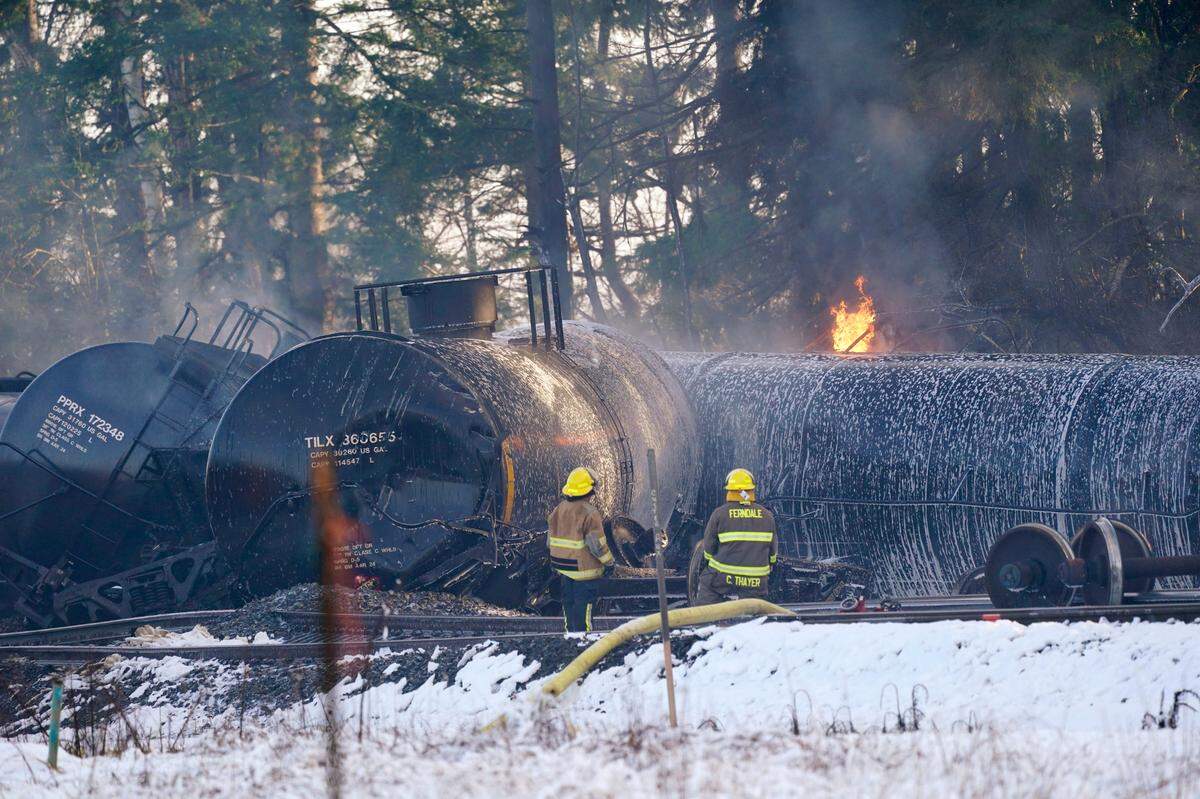 Firefighters look on as derailed train cars continue to burn Tuesday, Dec. 22, in Custer.