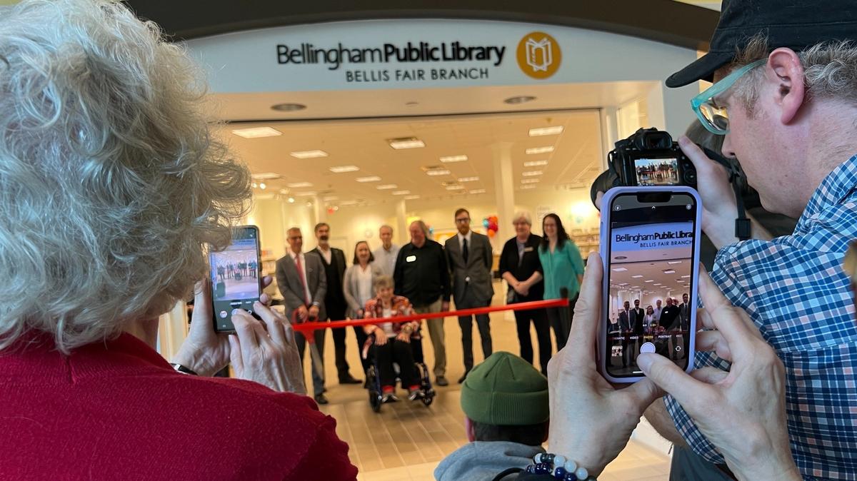 Library patrons take photos of the opening ceremony at the Bellingham Public Library’s new branch at Bellis Fair mall on Wednesday, April 26, 2023, in Bellingham, Wash.