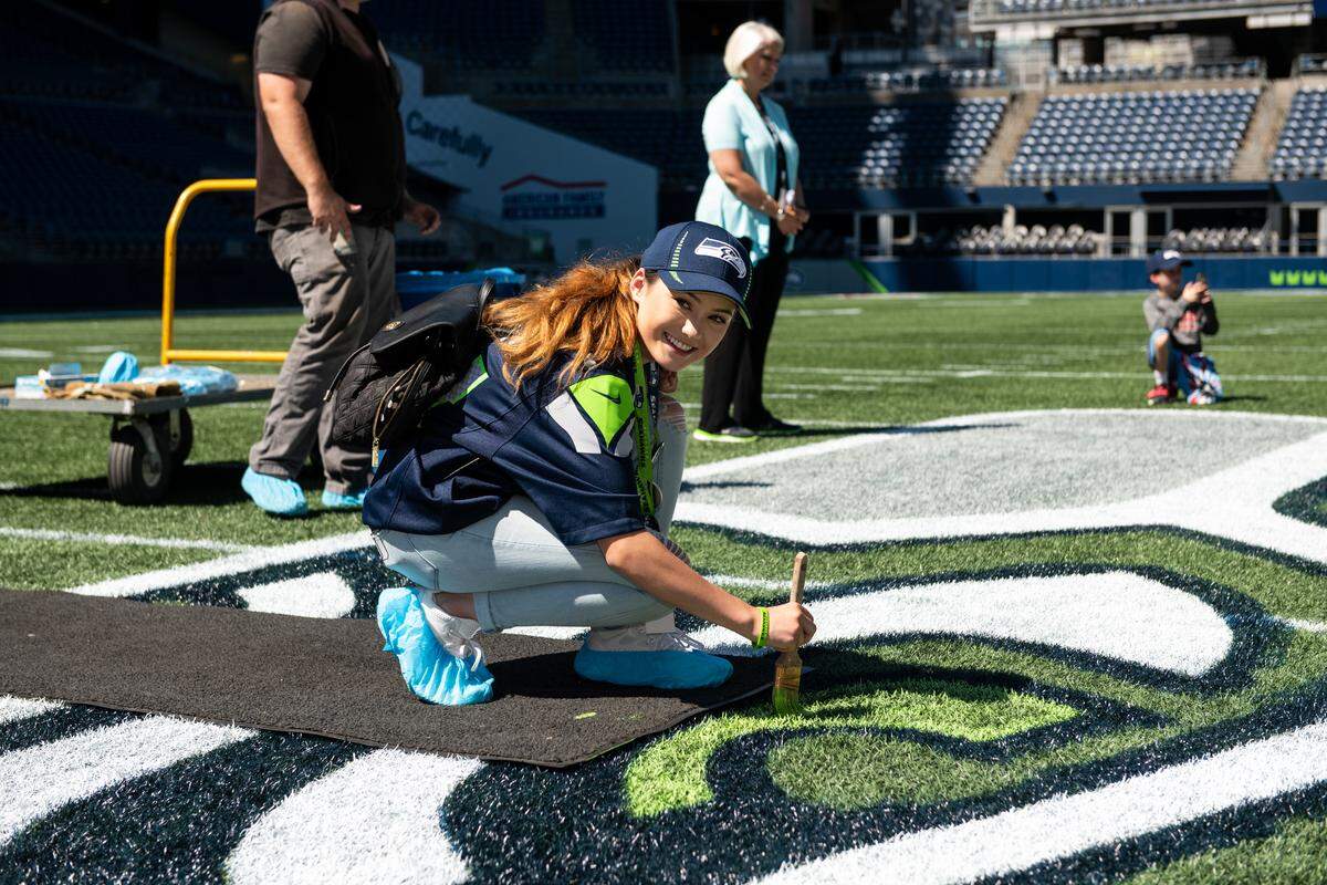 Squalicum senior Amber Louden, 17, helps paint the midfield Seahawks logo Aug. 7 at CenturyLink Field in Seattle during a Make A Wish visit with the Seathawks.