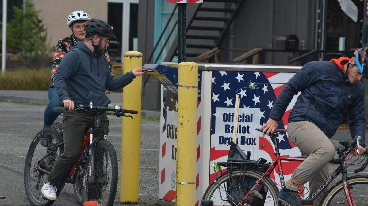 Bicyclists place their ballots in a drop box outside the Whatcom County Courthouse on Election Day.