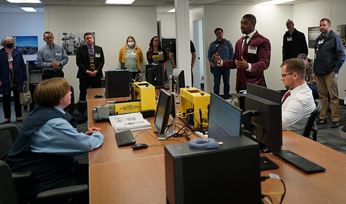 Whatcom Community College student Alambey Byrd, fourth from right, speaks at an open house for Whatcom Community College’s new Industrial Control Systems Cyber Range Wednesday, May 18, on Anvil Corp.’s campus near the Bellingham International Airport. The center focuses on training against cybersecurity attacks.