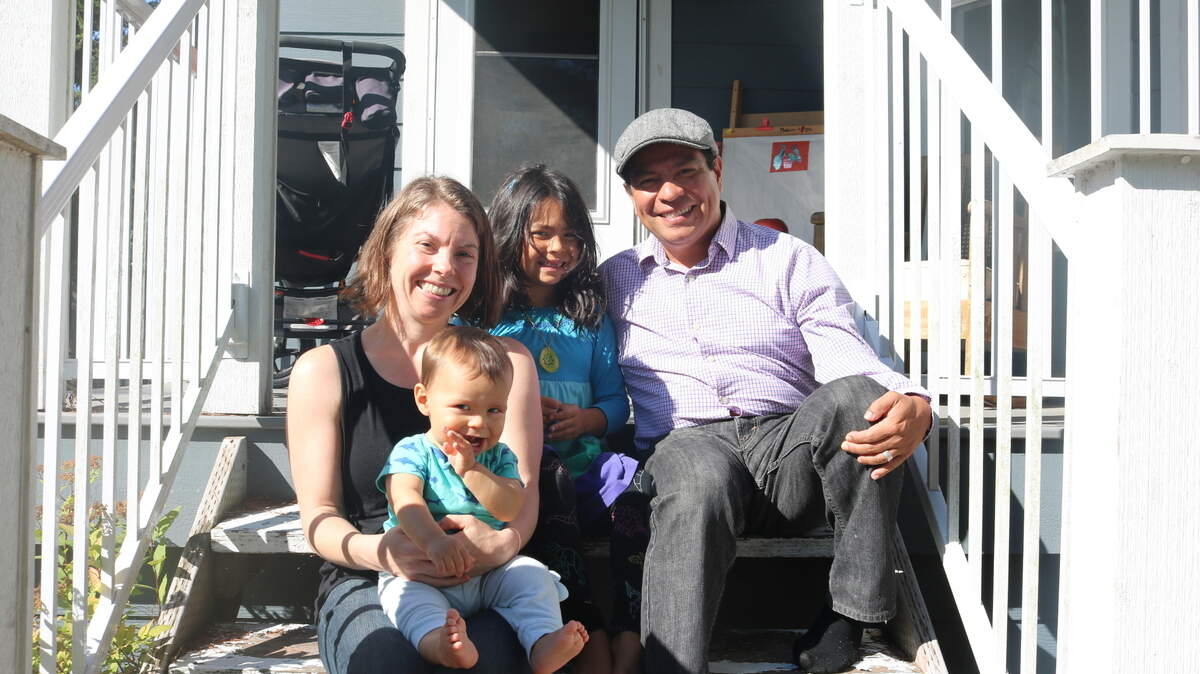 Kat McAvoy, left, and her husband Ario Salazar, right, sit with their two young children on the front steps of their home in the Happy Valley neighborhood of Bellingham on Aug. 27. The family reduced their home’s energy use by an estimated 85% through a deep energy retrofit.
