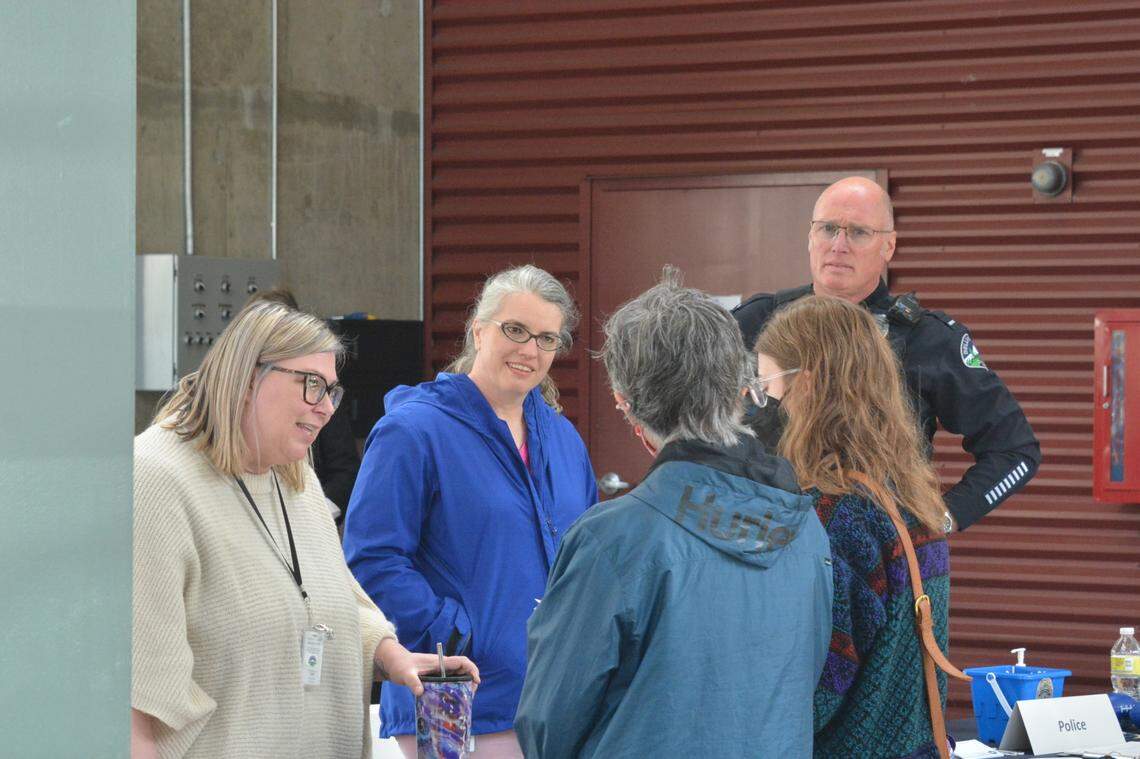 Bellingham Police Department employees talk to two job-seekers about job opportunities during a city-sponsored job fair on May 13, 2022, at Depot Market Square in Bellingham. From left are Michelle Doran, a dispatcher with the What-Comm 911 center, Ruth Baker, a receptionist at Bellingham Police headquarters, and Police Lt. Jason Monson.