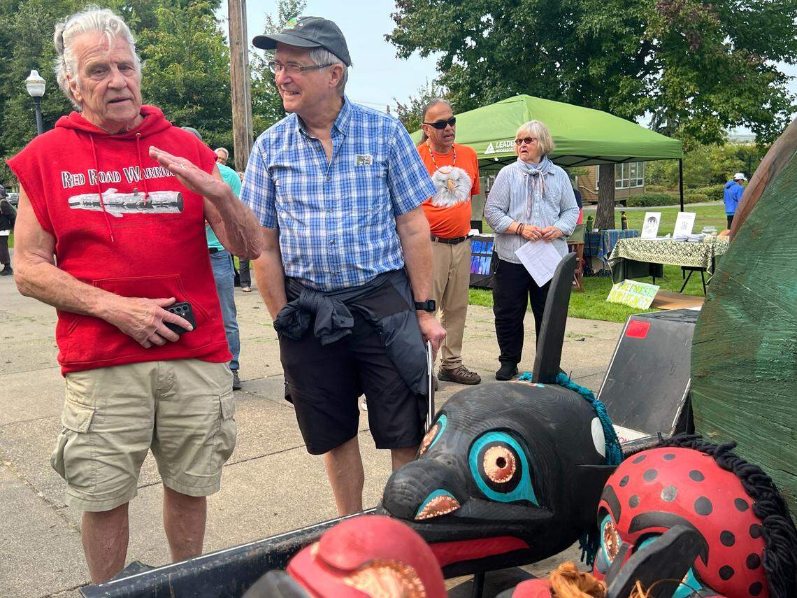 Kurt Russo, left, and David Roberts look at some of the ceremonial masks carved by Jewell James of Lummi Nation during the Xaalh and the Way of the Masks rally at Maritime Heritage Park in Bellingham on Saturday.