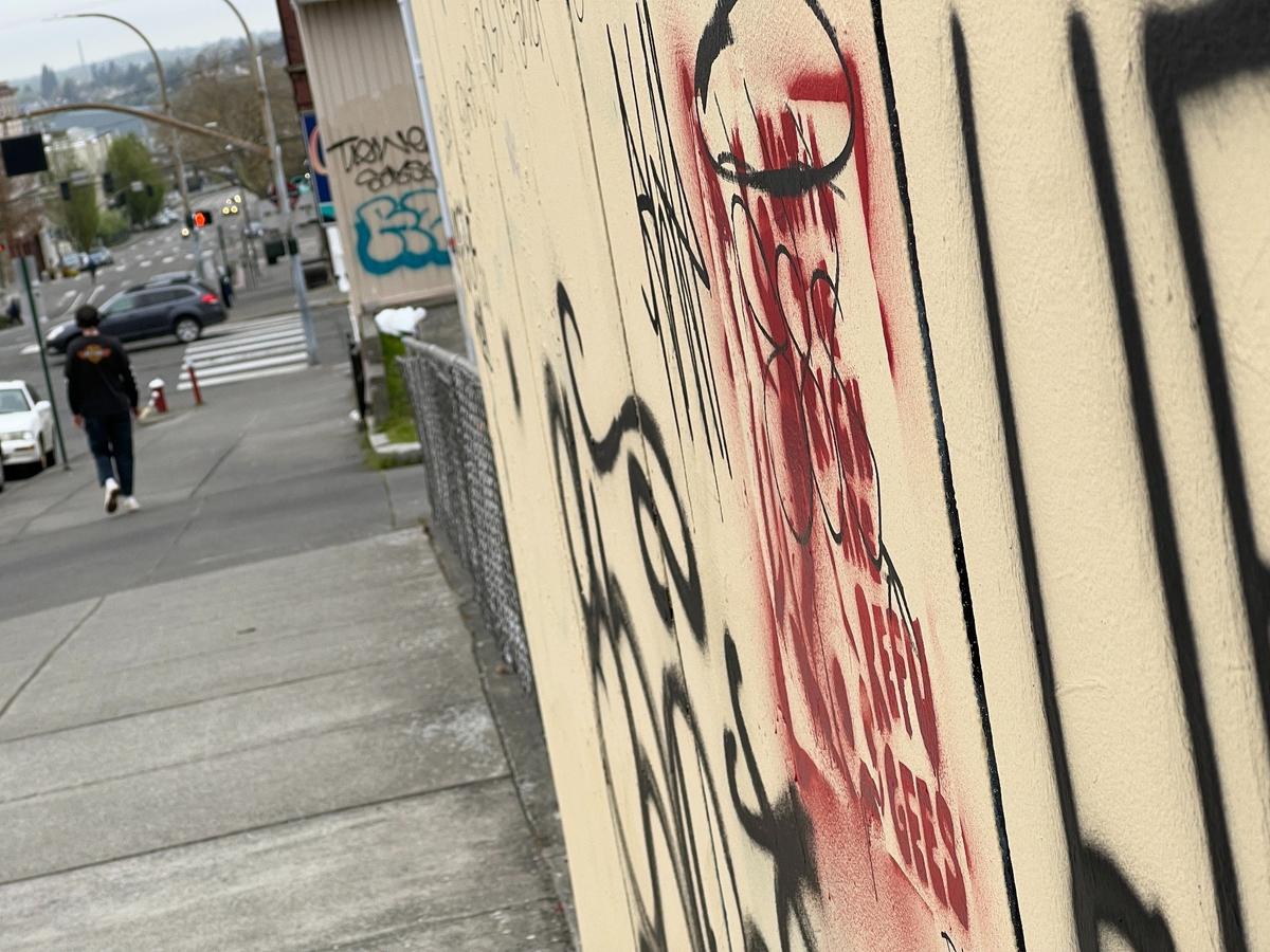 A pedestrian walks past a graffiti-covered wall on East Chestnut Street west of North Garden Street in downtown Bellingham, Wash., on Monday, May 1, 2023.