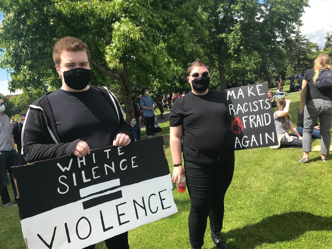 People hold up signs before a Solidarity Rally begins at 3 p.m. Saturday, June 6, at Maritime Heritage Park in Bellingham.