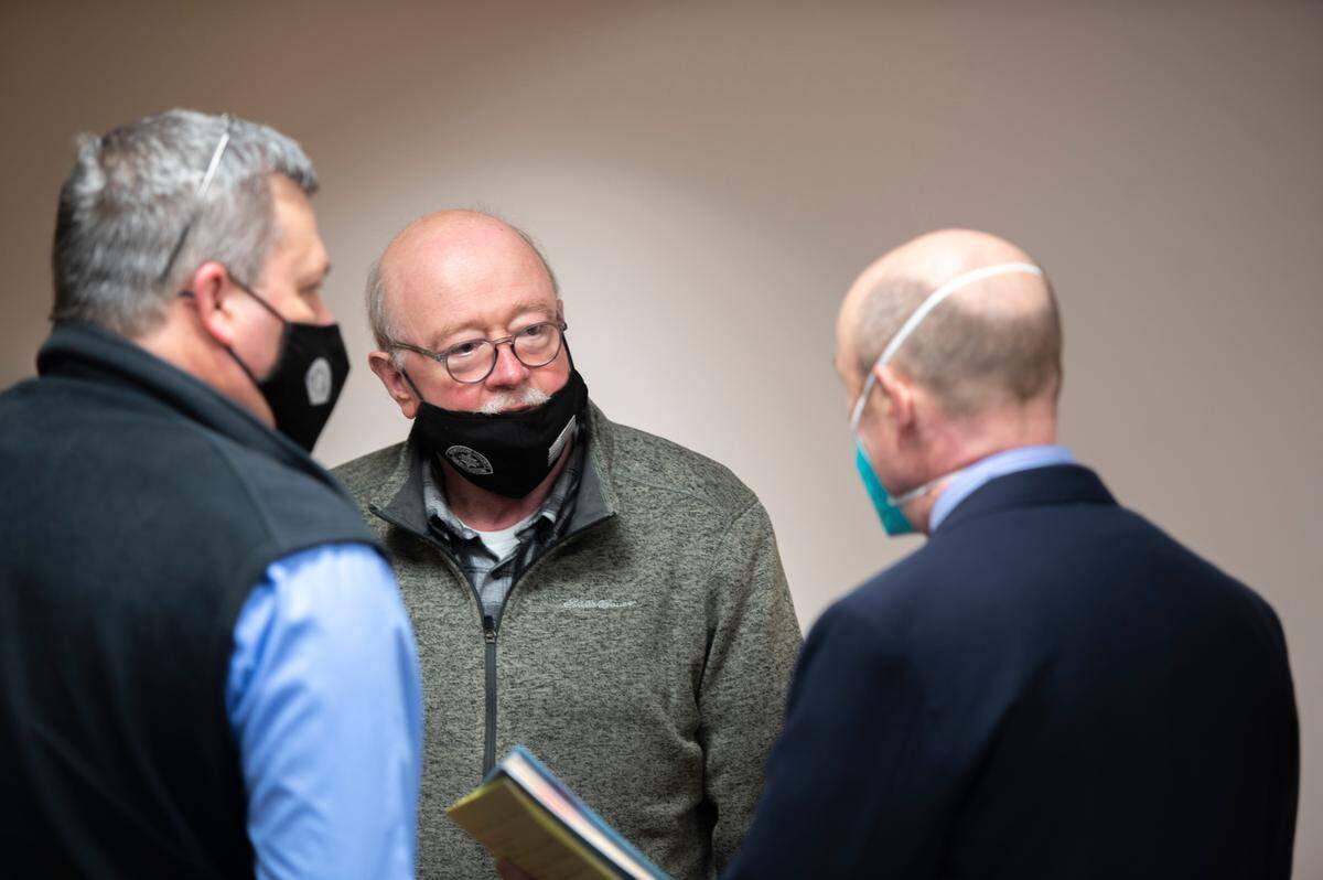 Whatcom County Sheriff Bill Elfo, center, speaks with attorneys before Joel Berck Young’s arraignment in Whatcom County Court on Friday, Feb. 18, in Bellingham. Young pleaded not guilty to charges stemming from the shooting and injuring of two Whatcom County Sheriff’s deputies last week.