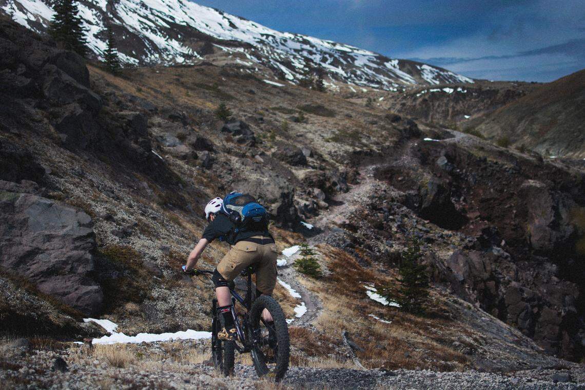 A biker rides Loowit Tier by Mount Saint Helens.