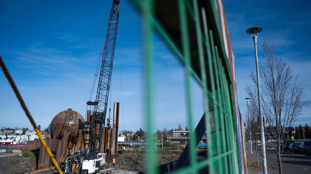 Construction crews use a crane to drive piling at the future site of 94 condominium units on the waterfront on Wednesday, Dec. 15, 2021, in Bellingham, Wash.
