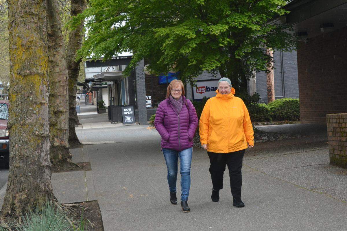 Debbie Price, left, and AnnMarie Jordan, both of Bellingham, walk along a shady section of East Holly Street in downtown Bellingham on Friday, May 6, 2022. According to a recent report, the city center has the least amount of tree canopy in the city.