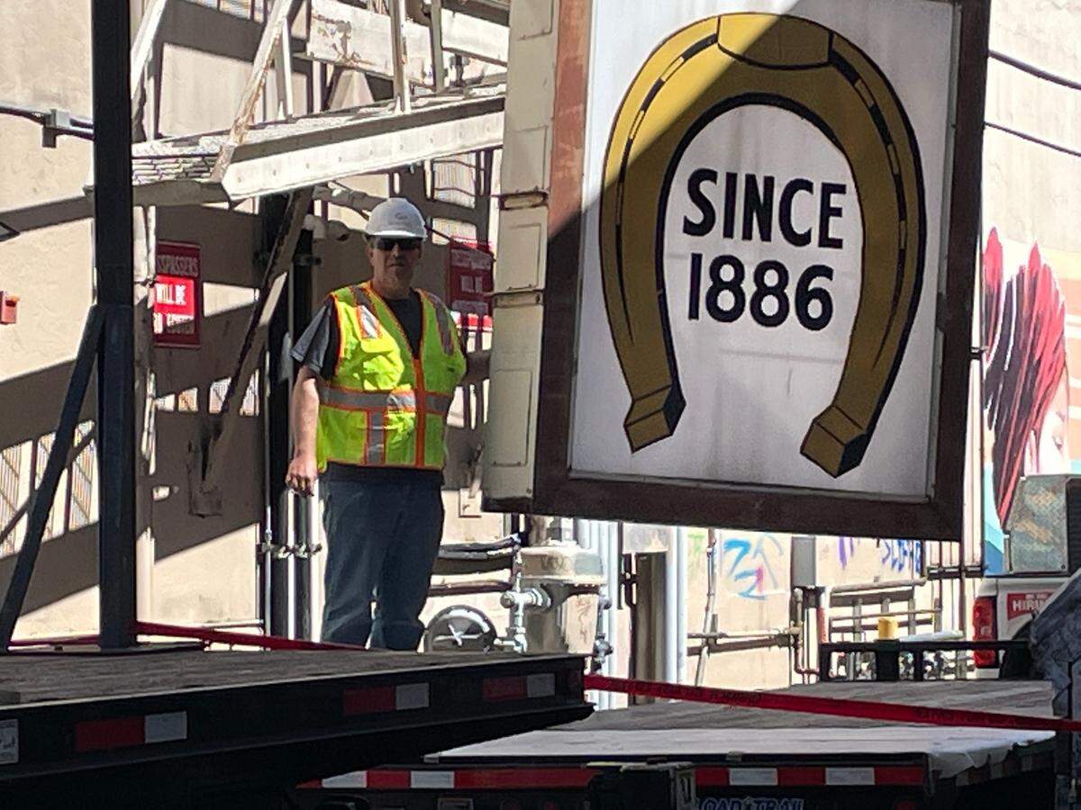 Steve Wydur of Signs Plus helps lower part of the Horseshoe Cafe sign onto a truck on Tuesday, June 7. The longtime Bellingham cafe is getting a new sign that will have a similar look but will be safer and have new features.