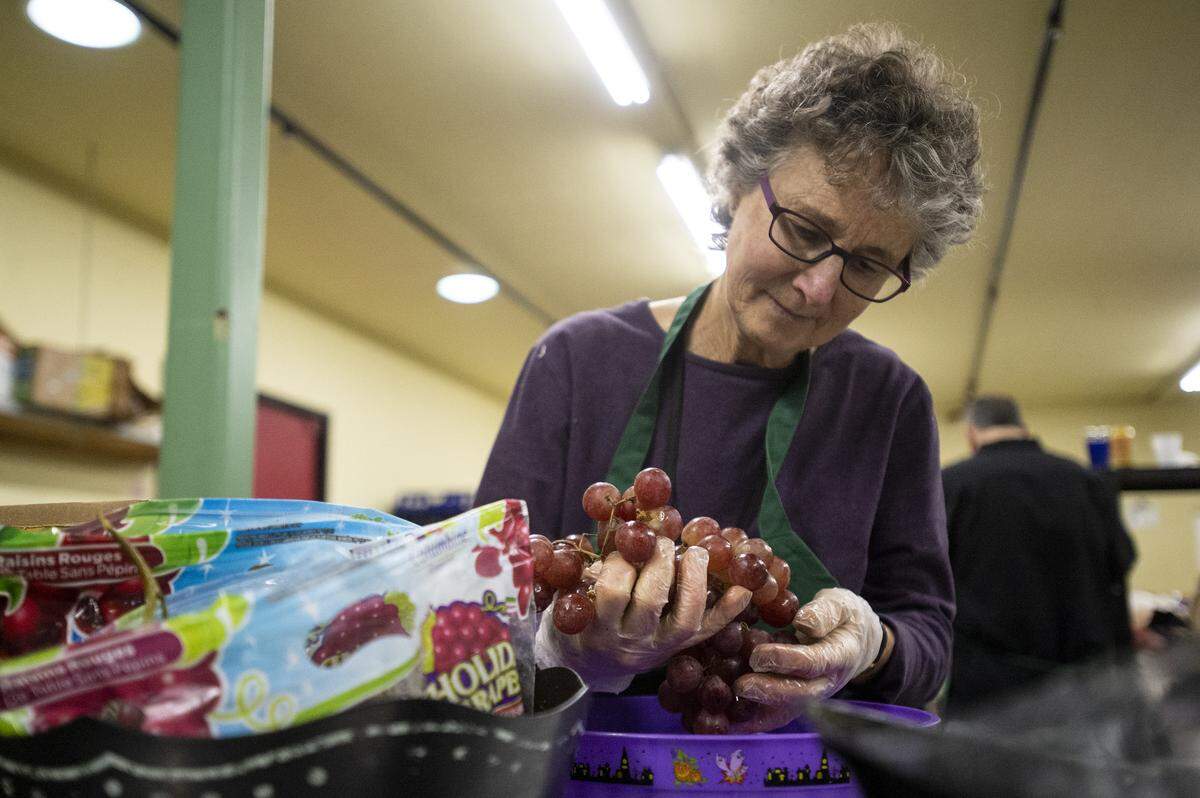 Vicki Roy, a substitute volunteer, sorts grapes and other fruits at the Bellingham Food Bank in January. A three-person household gets an average of $75 worth of food per visit to the food bank.