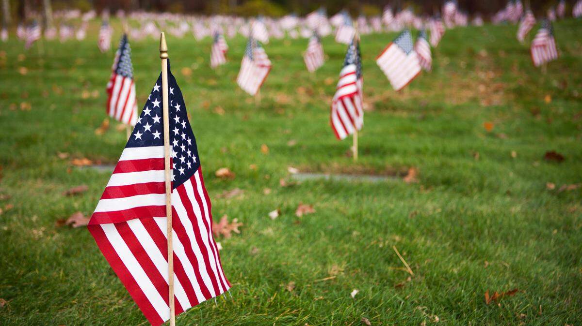 Small American flags are placed in front of graves at the National Cemetery in Bourne, Massachusetts.