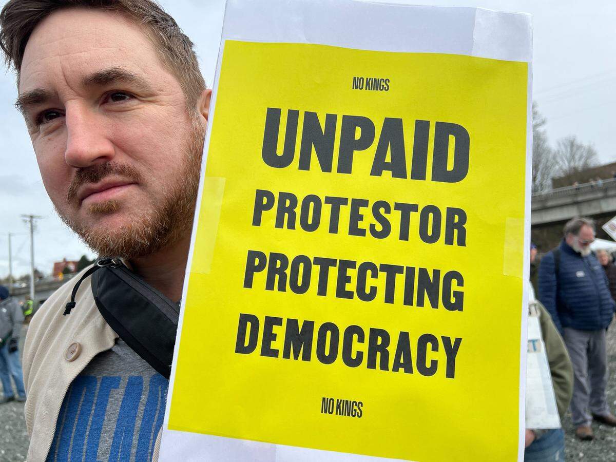 Jeremy Wright of Bellingham holds up a protest sign Saturday, March 28, 2026 during a local No Kings protest event in Bellingham.