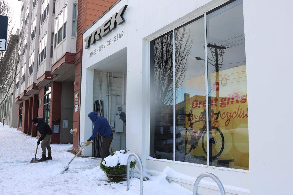 Trek Bicycle Bellingham staff members shovel snow Monday morning, Dec. 27, on East Chestnut Street in downtown Bellingham.