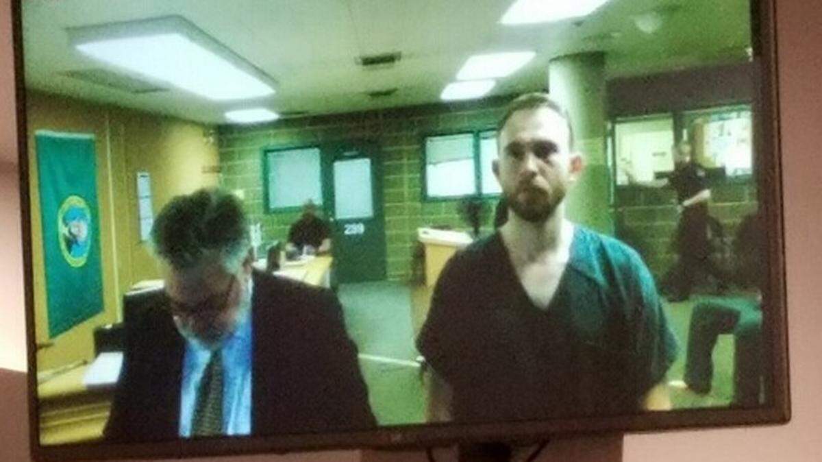 Alexander Vanags, right, appears on a video monitor in Whatcom County Superior Court in Bellingham, Wash., on Monday, April 15, 2019. He is facing a charge of second-degree murder for the death of Mark Stebakov, a friend he was camping with near Baker Lake.