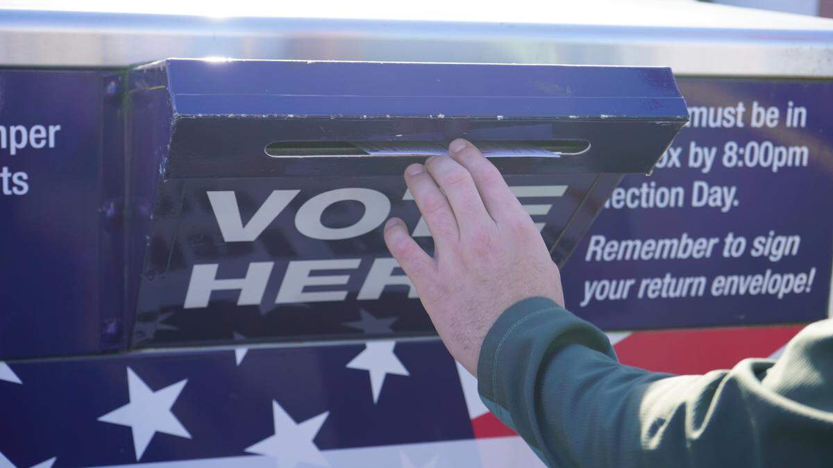 A voter drops their ballot in an official drop box near the Whatcom County Courthouse in 2022.