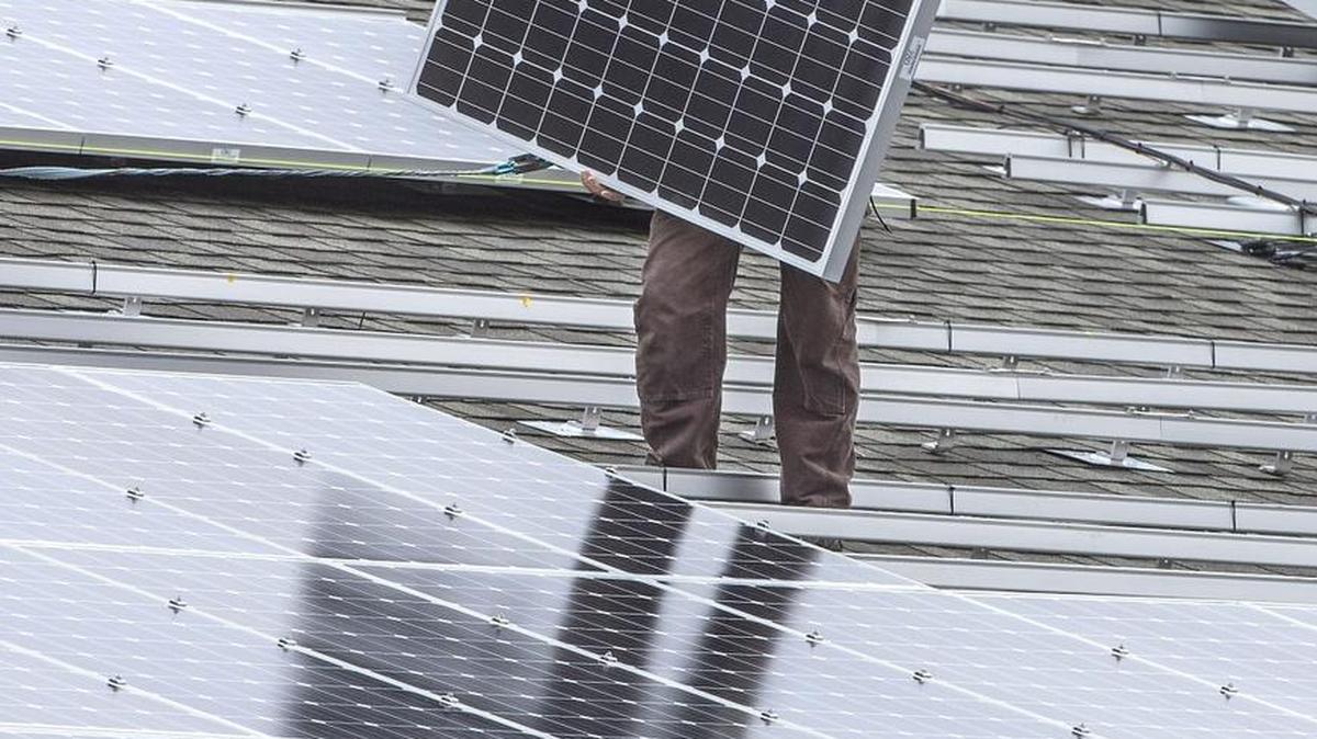 A worker for A & R Solar of Seattle lifts a solar panel from ITEK Energy of Bellingham into place on the roof of the Harbor History Museum in Gig Harbor. Peninsula Light Co. is using the roof as part of the Harbor Community Solar project, installing 216 panels as part of a 60-kilowatt solar energy system.
