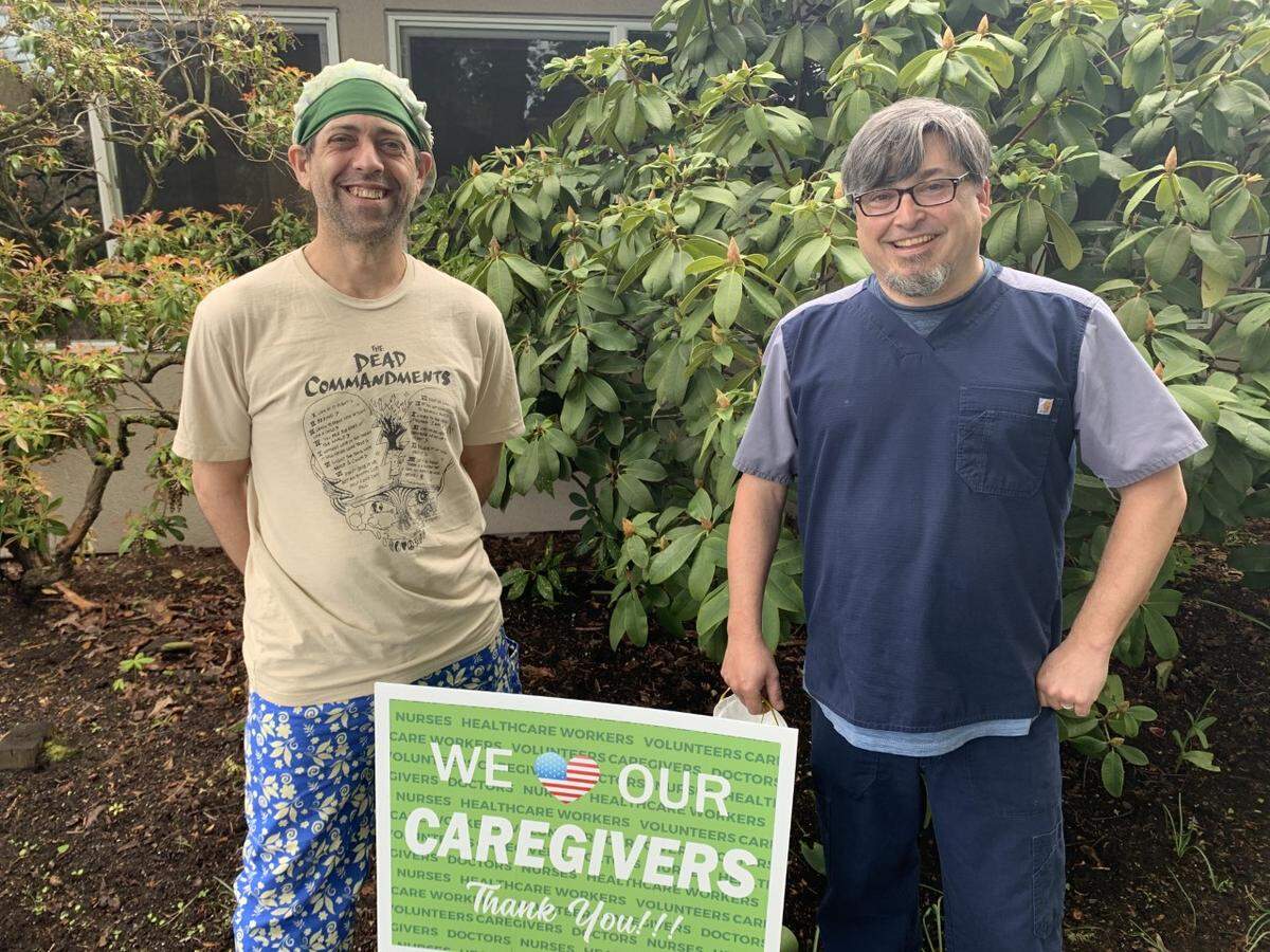 Shuksan Healthcare Center nurses Ryan Beeson, left, and Jason Wagner stand next to a sign the community placed in support of the Bellingham nursing home as it battled a coronavirus outbreak. “The outpouring from the community has been amazing,” Beeson told The Herald.