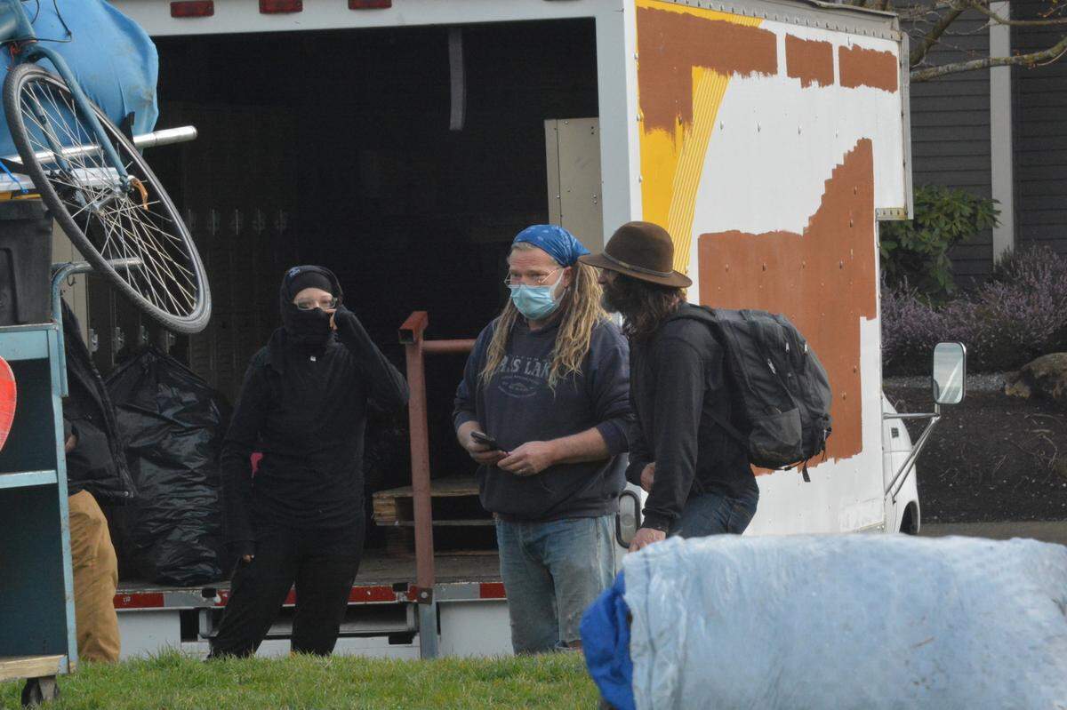 Homeless advocate Markis Stidham, center, chats with his friend Jack Smith, right, on Thursday, March 25, at Laurel Park in Bellingham. Stidham was helping people move their belongings from a homeless encampment at the park. Smith is without permanent shelter often lives on the streets.