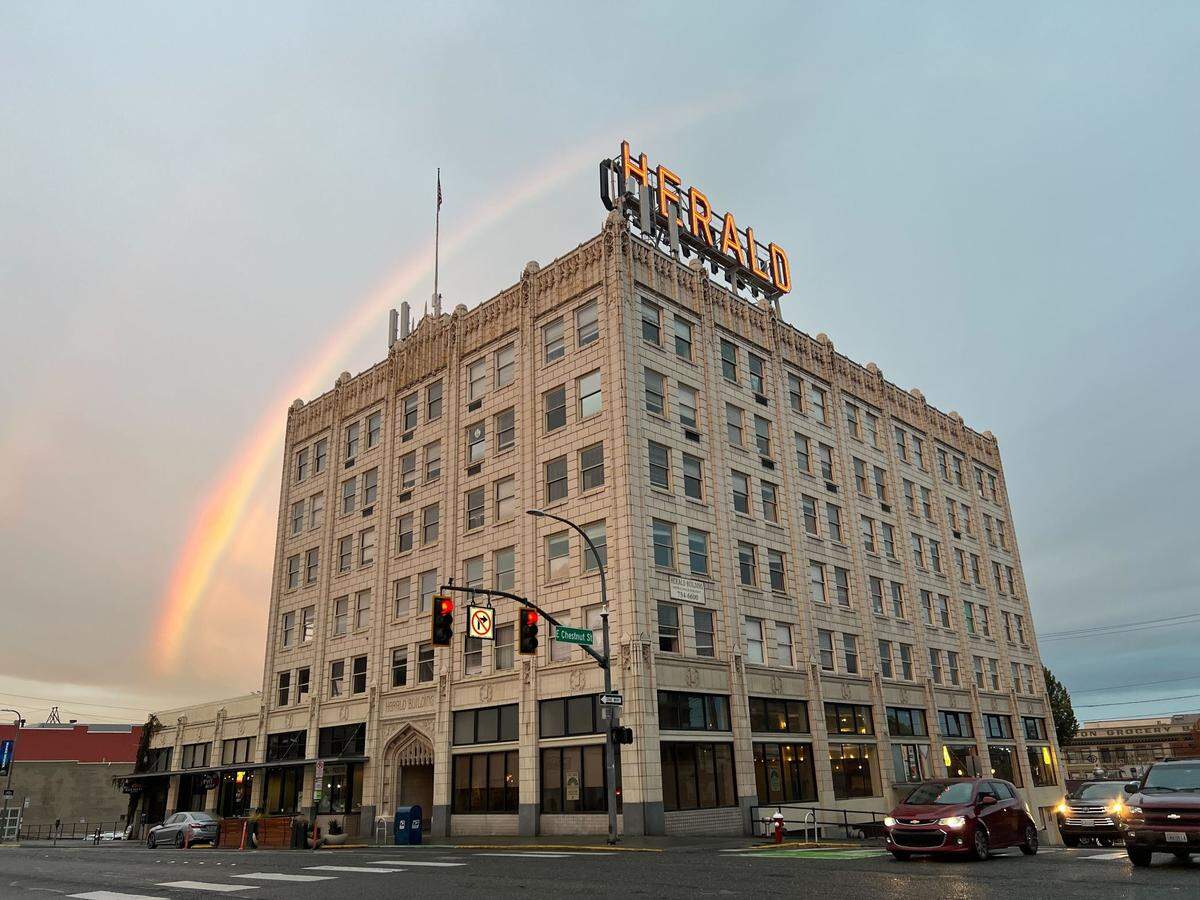 A rainbow arcs above the Herald Building at the corner of North State and East Chestnut streets in Bellingham, Wash., on Oct 19, 2023. Built in 1926, the six-story Gothic Revival building uses white terra cotta tiles and stained glass windows depicting a herald playing a trumpet. The building was the first in downtown Bellingham to use a concrete-and-steel form and steam for heating. It’s on the National Register of Historic Places.