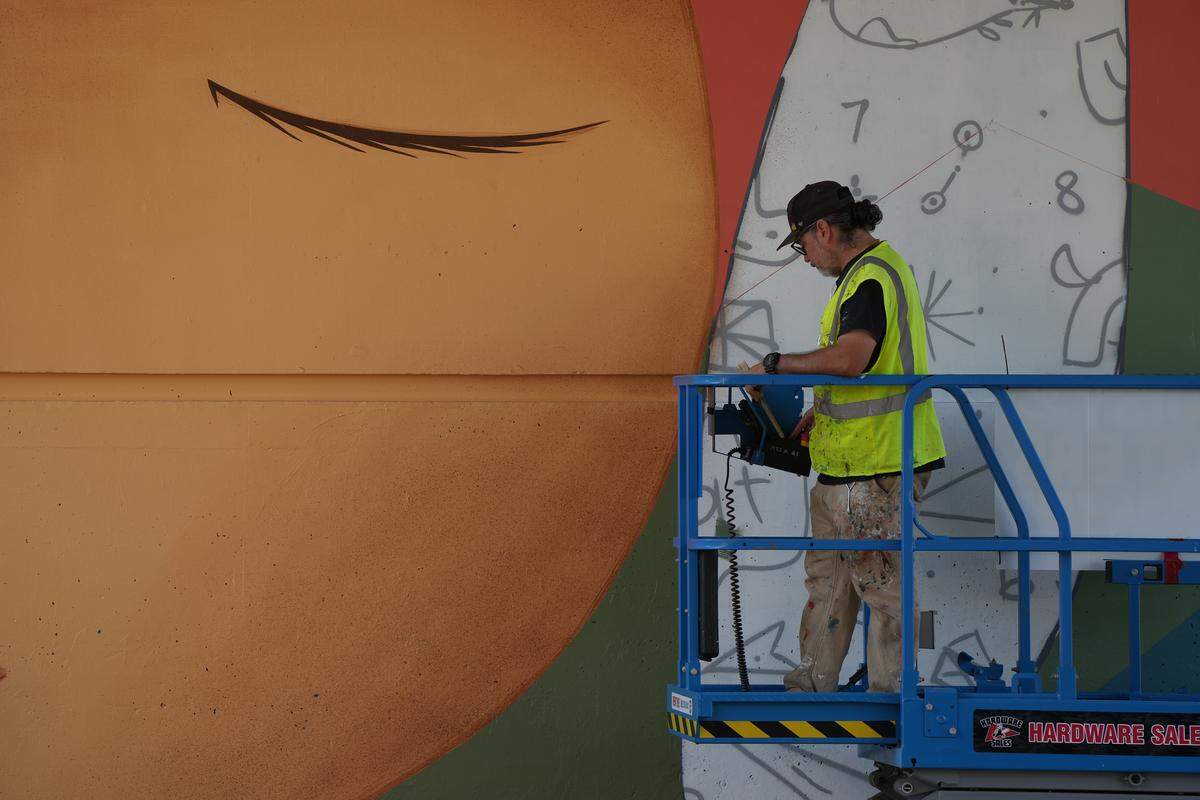 Denver-based street artist Jaime Molina works on his new mural on Aug. 26 underneath the I-5 overpass on Lakeway Drive.